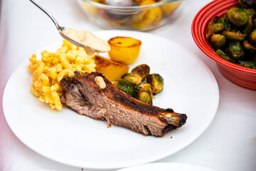 Sauce Drizzle Over Mac and Cheese with Grilled Meat, Roasted Brussels Sprouts, and Charred Lemon