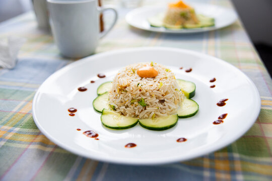 Steamed Rice with Cucumber Garnish and Sauce Drizzle &ndash; Elegant Minimalist Plating as main course, a mug and the second plate is in the blurred background in this home cooked meal 