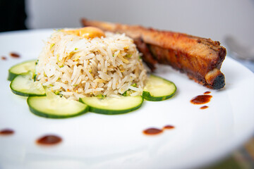 Grilled Meat with Steamed Rice and Cucumber Garnish – Elegant Plated Meal Presentation in food and restaurant industry. 
