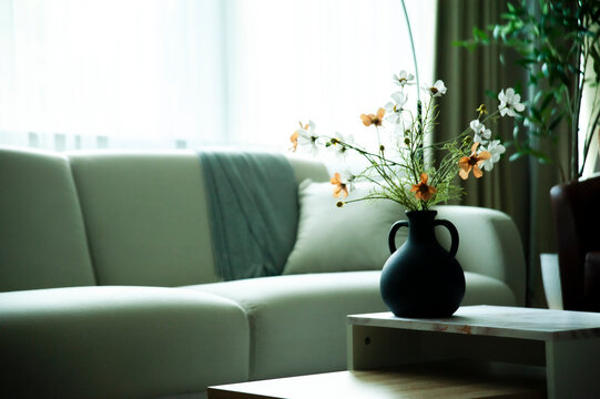 Simple and elegant home decorations in the living room that showcase luxury, with a flowerpot on the coffee table holding just enough flowers to convey simplicity and luxury.