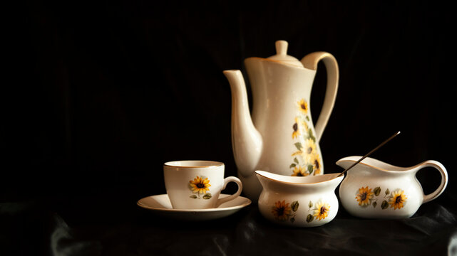 Travel and tourism industry using vintage teapots and teacups to serve tourists, with the teapot and teacups set against a black background.