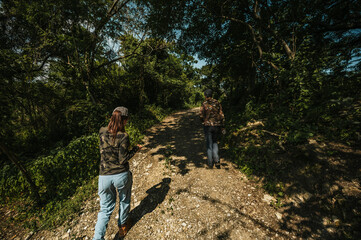 Naklejka premium Mother and daughter dressed in hiking clothes, walking along a trail in the middle of the rainforest.