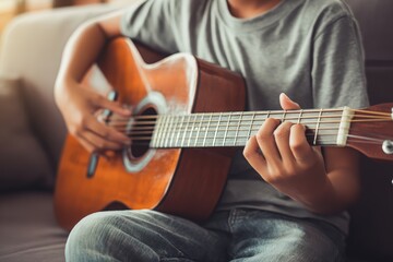 Fototapeta premium Young person playing acoustic guitar at home, close-up of hands strumming strings, relaxing musical hobby, casual indoor lifestyle, artistic self-expression in a comfortable setting