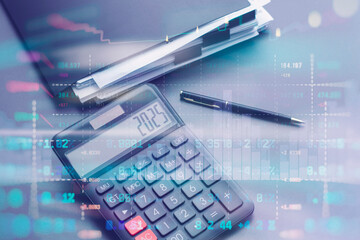 Digital calculator showing 2025 on display with business pen and documents with financial data...