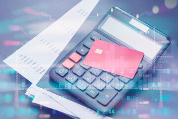 Red credit card, calculator and documents on a table in office with stock market data overlay. Technology concept personal finance, budgeting, online payments and accounting.