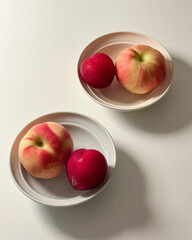 Two peaches and two apples on plates.
