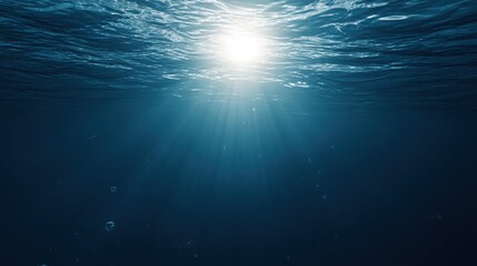 Obraz premium Sunlight streams through ocean waves, creating a mesmerizing play of light and shadow in deep blue waters.