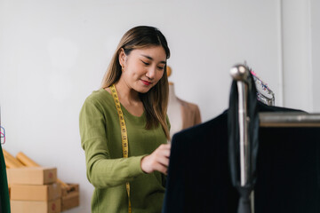 Asian fashion designer working on new clothes collection in her workshop