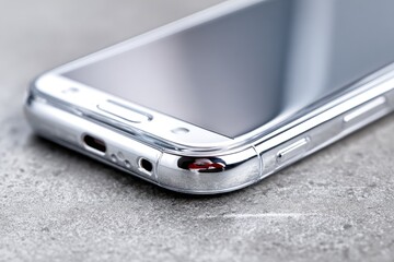 Close-up of a silver smartphone on a textured surface
