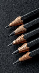 Close-up of several black pencils on dark surface