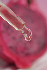 A dropper releases clear liquid onto a vibrant against dragon fruit ,