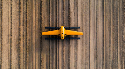 Aerial view of a small yellow drone on a wooden surface.
