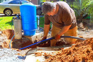 Man works on installing plumbing system next to blue tank in home under connect to water well