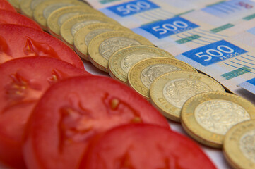 Rows of tomatoes and currency of Mexican peso banknotes and coins, trade concept