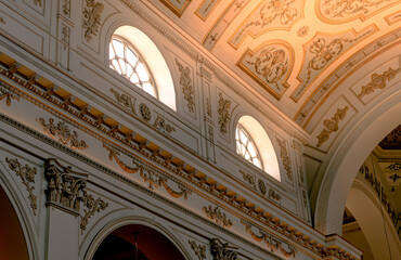 Historic architecture of a grand interior featuring ornate designs and natural light streaming through arched windows