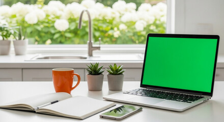 Laptop with green screen on a white kitchen table with coffee and notebook