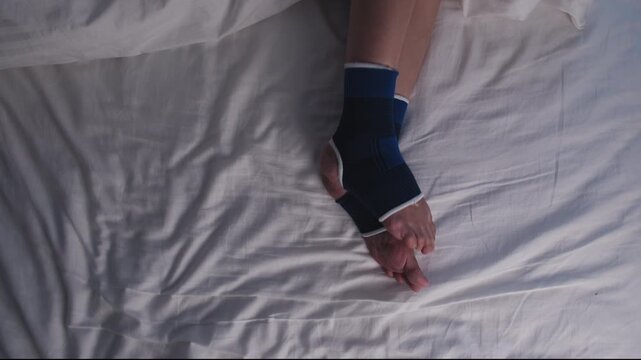 Close-up, woman's irritated legs with ankle support, sleepless from restless leg syndrome, awake at night on bed, with insomnia illness, itching and discomfort problems from healthcare lifestyle.