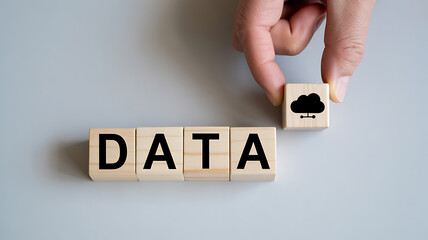Hand placing a wooden block with a cloud icon next to wooden blocks spelling out data representing cloud data storage and digital information