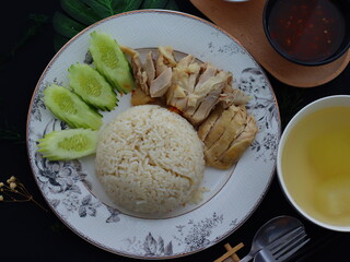 Khao Man Gai — Thai-style Hainanese chicken rice featuring tender boiled chicken served with aromatic chicken oil rice, rich soy-based dipping sauce, and fresh cucumber slices. A beloved Thai comfort 