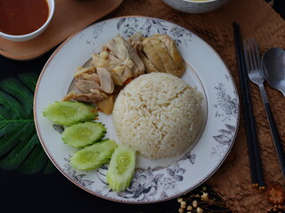 Khao Man Gai — Thai-style Hainanese chicken rice featuring tender boiled chicken served with aromatic chicken oil rice, rich soy-based dipping sauce, and fresh cucumber slices. A beloved Thai comfort 
