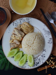 Khao Man Gai — Thai-style Hainanese chicken rice featuring tender boiled chicken served with aromatic chicken oil rice, rich soy-based dipping sauce, and fresh cucumber slices. A beloved Thai comfort 