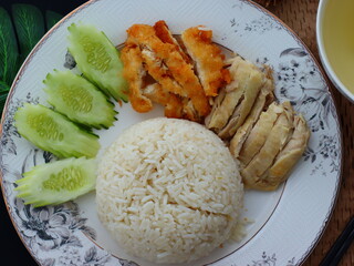 Khao Man Gai — Thai-style Hainanese chicken rice featuring tender boiled chicken served with aromatic chicken oil rice, rich soy-based dipping sauce, and fresh cucumber slices. A beloved Thai comfort 