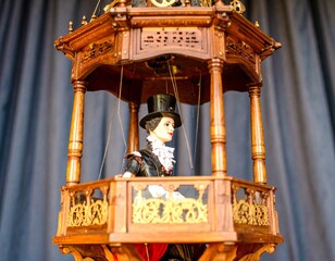 精巧な木製バルコニーに立つチェコ風衣装の操り人形を描いたクラシカルなイラスト