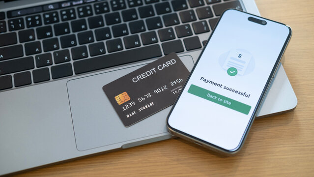 A credit card on a laptop next to a phone displaying successful payment, representing secure online shopping and fast checkout with just a few clicks - Powered by Adobe