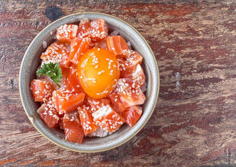 Top view of slice fresh salmon topping on rice with white sesame and egg yolk