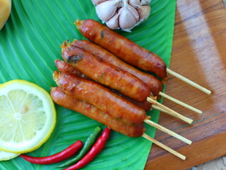 Grilled fermented pork sausage (Naem Yang) — a popular Thai snack with tangy, smoky flavors, grilled to perfection for a crispy exterior and chewy inside.

