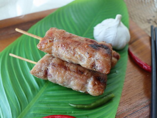 Grilled fermented pork sausage (Naem Yang) — a popular Thai snack with tangy, smoky flavors, grilled to perfection for a crispy exterior and chewy inside.