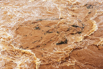 Smudged water flows profusely. River water flowing profusely. Flood waters rushing down river after storm flows through. Turbulent river dam. Water turbulence of river due to dam. Water Nature Texture