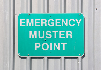 Emergency Muster Point safety sign attached to a metal corrugated wall