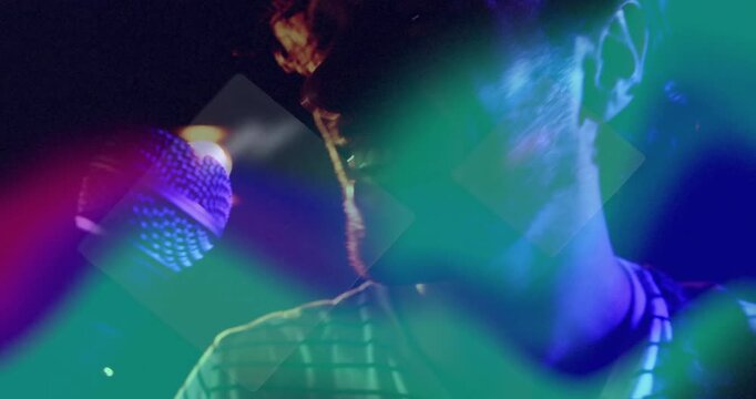 Male singer leaning into microphone starting singing as geometric overlays pulse on stage