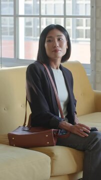 Vertical video: After scrolling phone diverse pair shaking hands conversing at lounge for interview