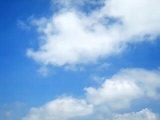 Obraz premium Clear blue sky with soft white clouds. Bright summer sky background. Soft white clouds float in the clear blue sky. Clear blue sky, bright spring, soft sky gradient, wallpaper landscape, aerial view.