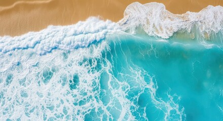 Aerial view of turquoise ocean water washing onto a golden sand beach on a sunny day
