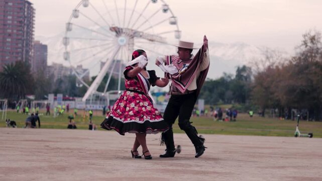 Smiling young couple dressed as Chilean huasos, joyfully dancing cueca outdoors. Traditional Chilean dance. Chilean traditions, celebrations.