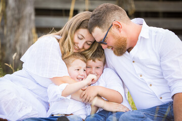 Family portrait sitting together on grass in front of shearing shed on farm
