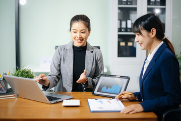Two businesswoman discuss investment project working and planning strategy with tablet laptop computer in modern office.