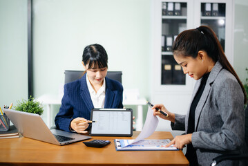 Two businesswoman discuss investment project working and planning strategy with tablet laptop computer in modern office.