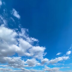 Obraz premium A vast expanse of bright blue sky dotted with fluffy, white clouds. A sense of freedom and endless possibilities. Peaceful and serene