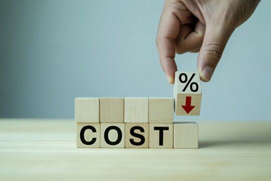 Hand places cube showing percentage and down arrow on blocks spelling cost