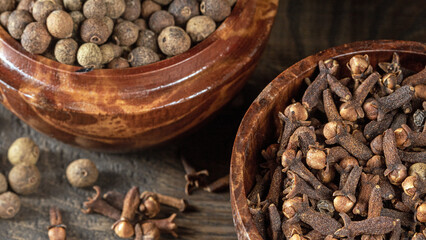 Close-up image of wooden cups filled with fragrant cloves and peppercorns
