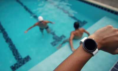 Person wearing smartwatch near pool with swimmers