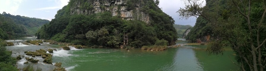 clear green river flowing around mountains in Yunnan China 