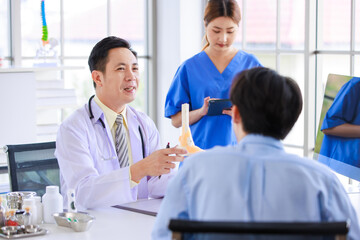 Obraz premium Asian male doctor consulting explain medications to senior female patient assisted by caregiver and nurse professional support trust healthcare checkup, insurance treatment wellness in hospital clinic