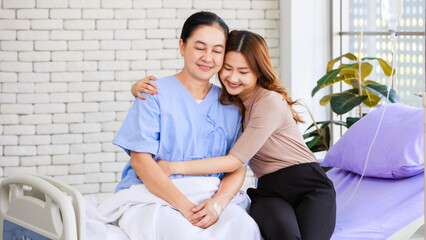 Obraz premium Asian happy family emotional support smiling elderly senior woman mother patient sitting hugging with lovely daughter cheering on hospital bed showing take care healthcare insurance treatment wellness