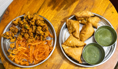 indian traditional snacks samosa, pakode, and jalebi with green chutney at indoor