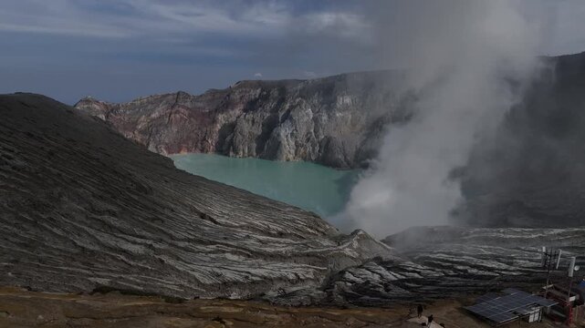 Steep rocky trail leads to Kawah Ijen's steaming crater and bright blue volcanic lake in Indonesia